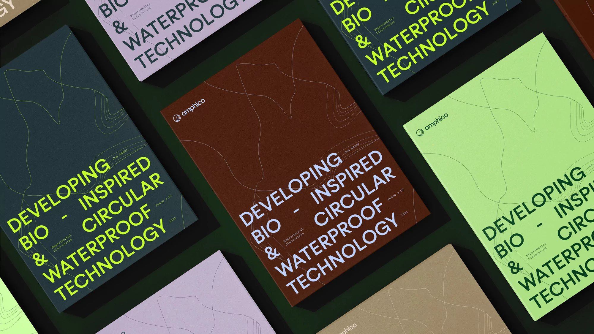 Close-up of multiple printed covers arranged on a dark green surface, each displaying a modern design and the brand logo 'amphico'.