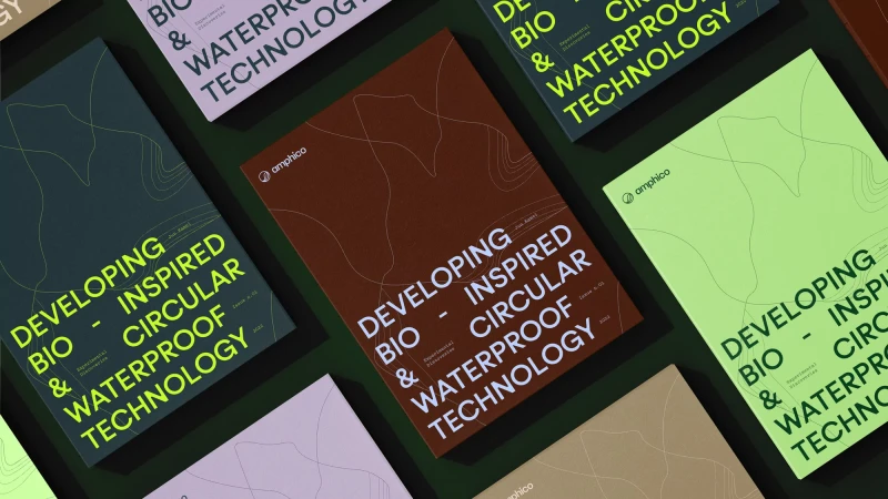 Close-up of multiple printed covers arranged on a dark green surface, each displaying a modern design and the brand logo 'amphico'.