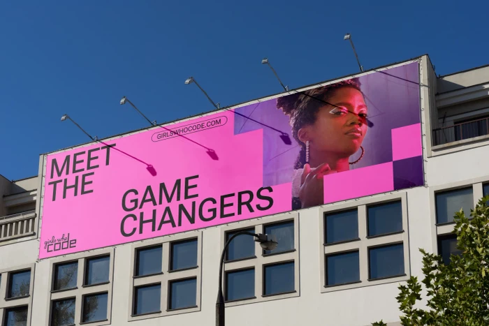 Large pink and purple Girls Who Code billboard reading Meet the Game Changers mounted on a light-colored urban building exterior