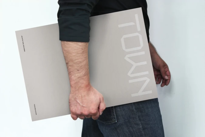 An adult holds a poster featuring the word 'Town' in white block letters against a gray backdrop, showcasing contemporary design.