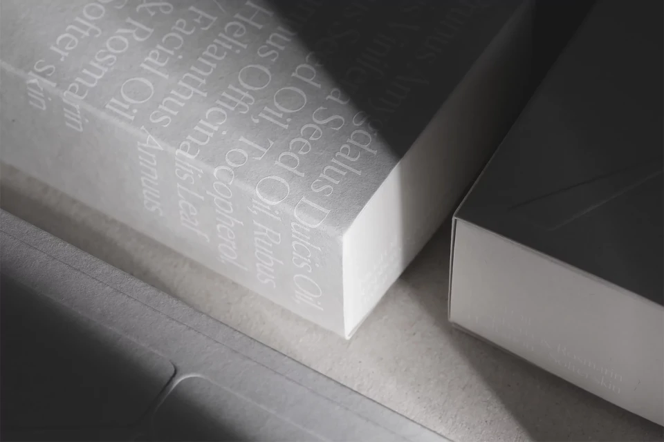 Close-up of white packaging boxes with visible ingredient text in an indoor setting, illuminated by a beam of light.