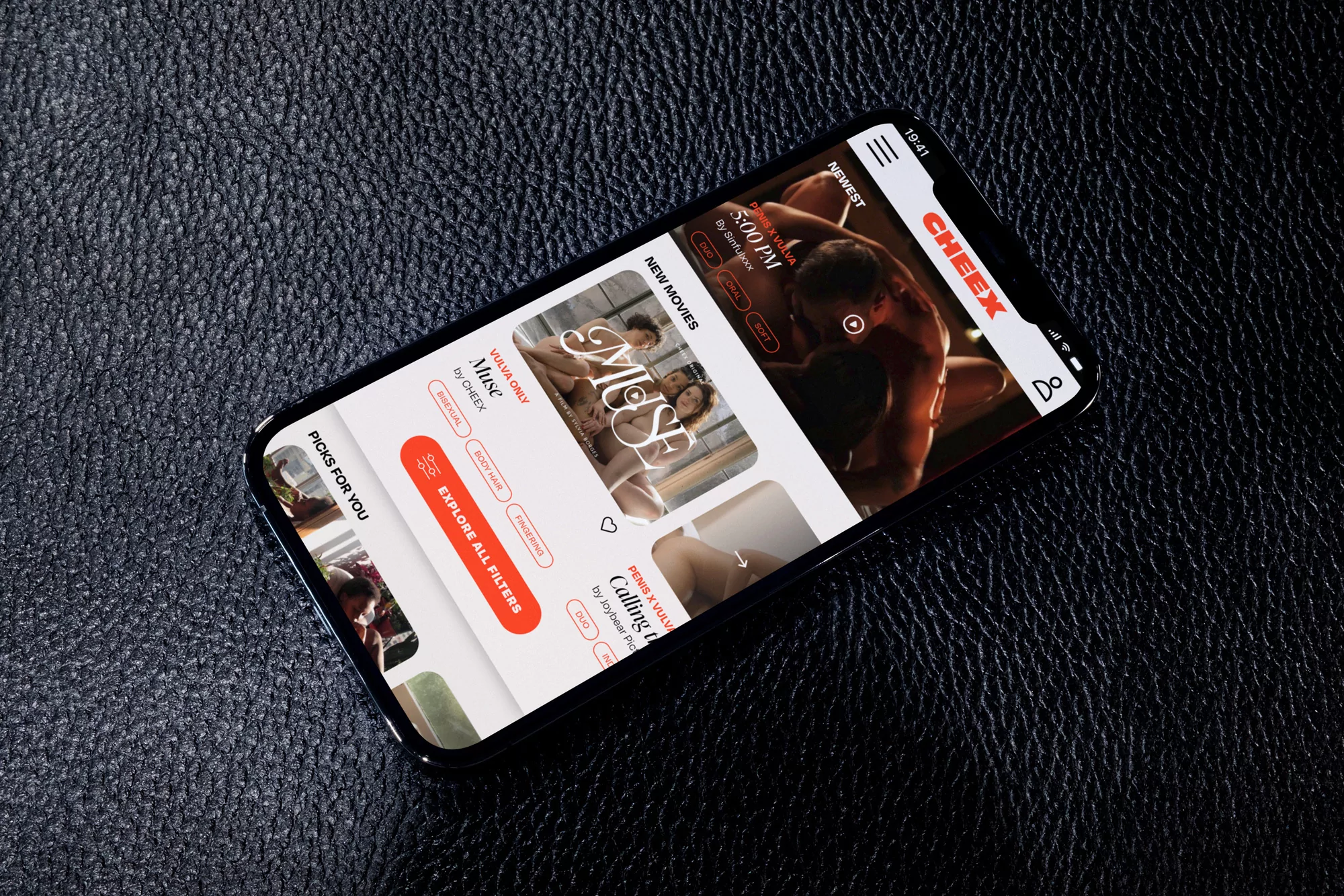An iPhone displays the Cheex app with several thumbnails on a dark leather surface, capturing a close-up view of mobile technology.