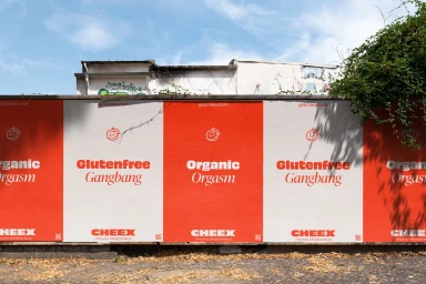 CHEEX outdoor brand identity posters with red and white panels displayed on a city wall under a clear sky.