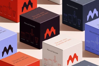 Colorful product packaging boxes in red, dark brown, purple, and cream arranged on a pale surface.