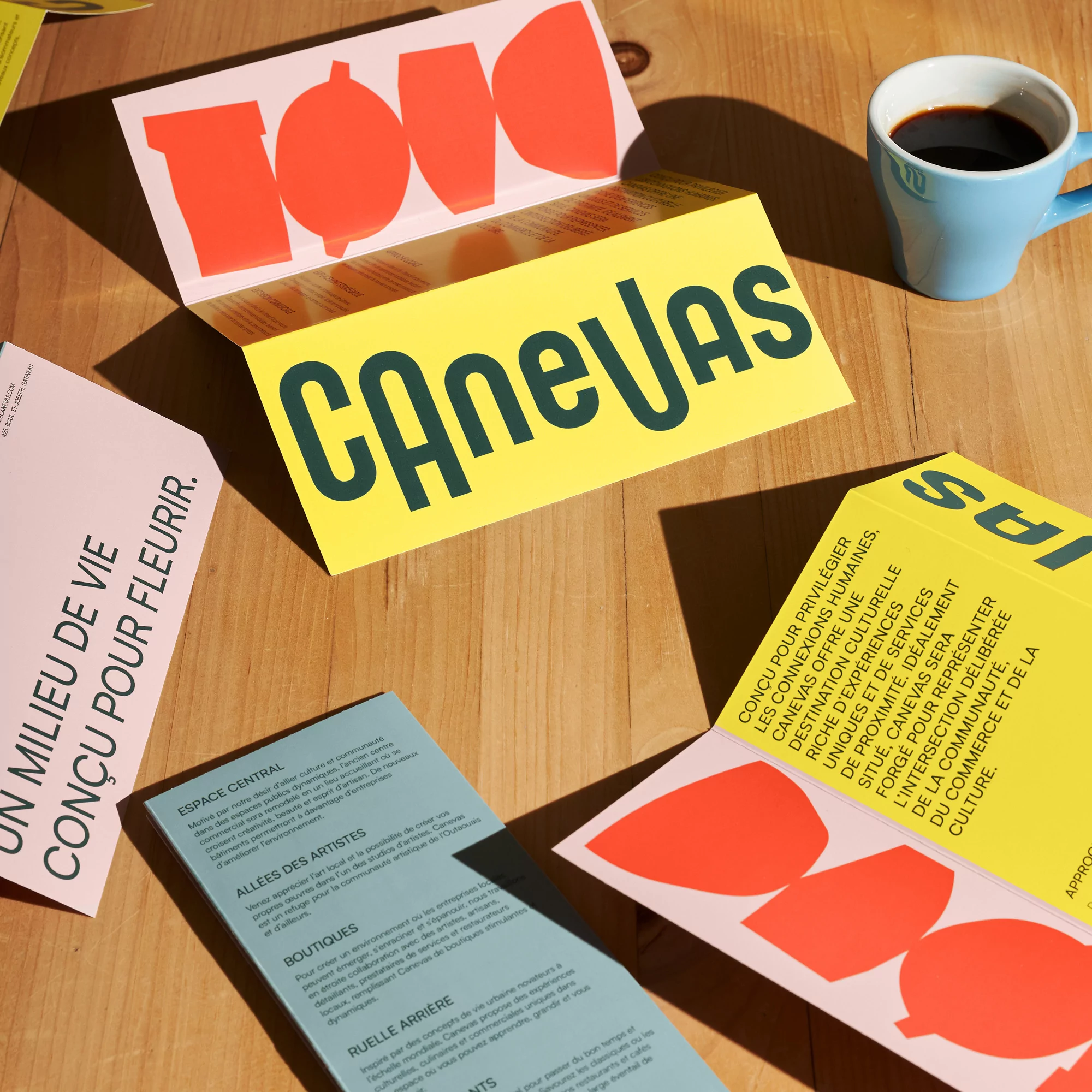 Overhead shot of colorful graphic cards with bold text, a blue mug with coffee, and a light wood table, creating a modern, stylish visual.
