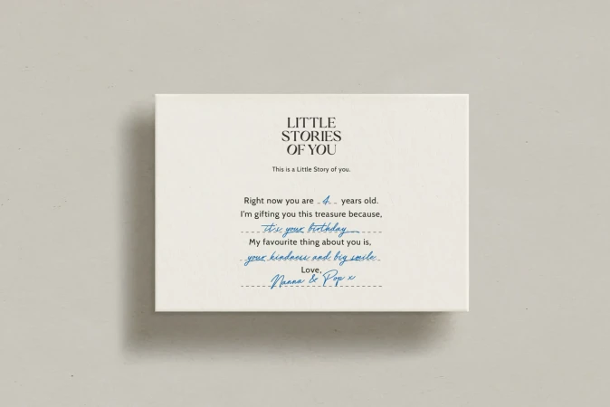 Close-up of a white box with black and blue handwritten-style text, featuring a personalized story and birthday message.