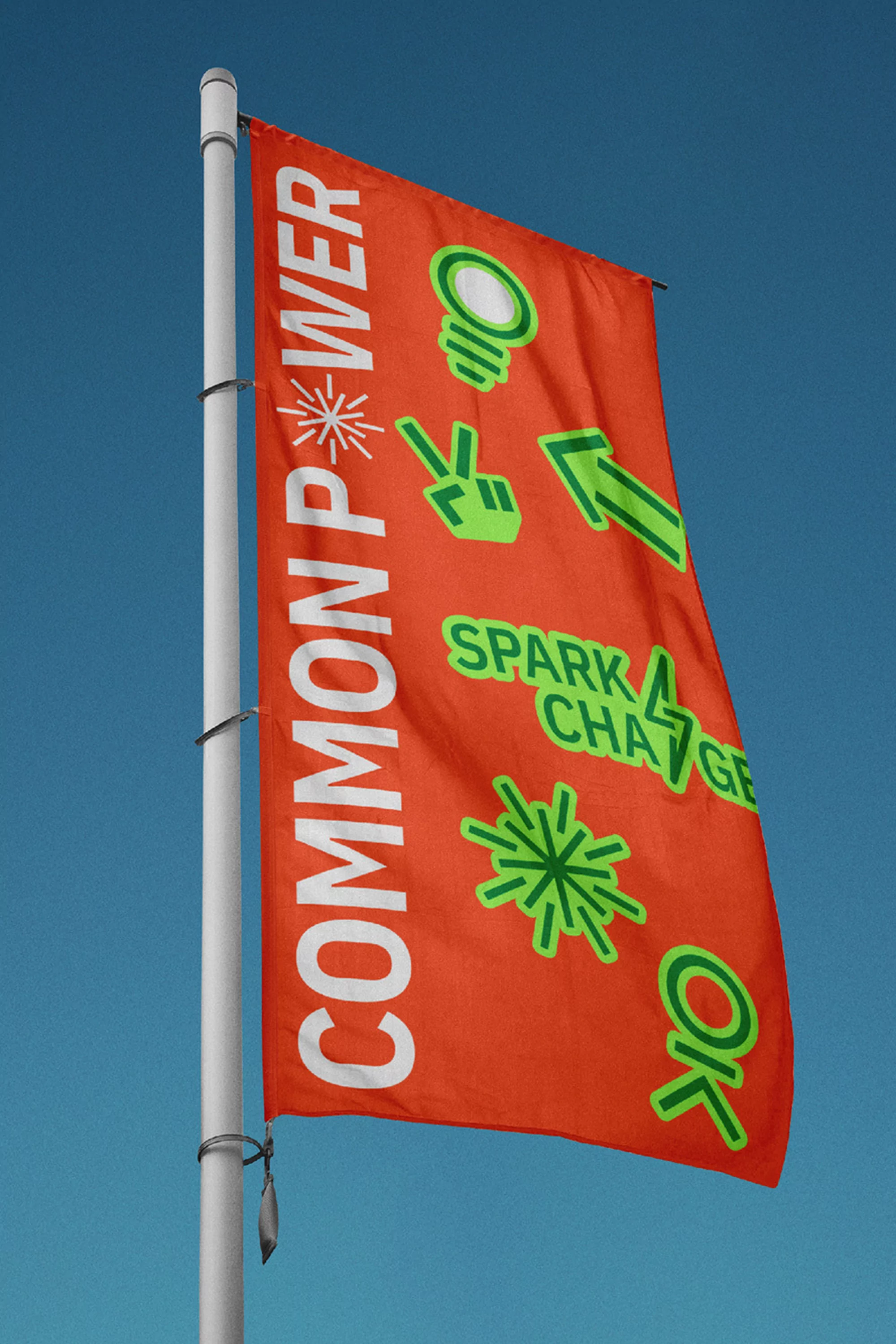 Bright orange flag on a pole against a blue sky, featuring white lettering and green graphics, flying outdoors during daylight.