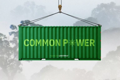 A green shipping container suspended by cables against a foggy forest background with branding for Common Power.