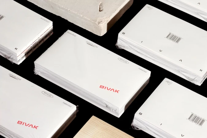 Stacks of shrink-wrapped white books with red typography on a black background