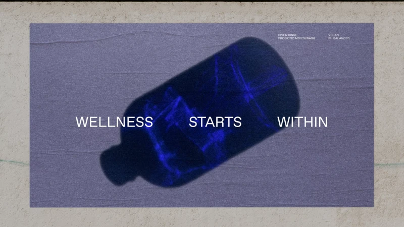 A bottle of mouthwash with the text 'Wellness Starts Within' in a stylized product shot with purple and blue color grading.