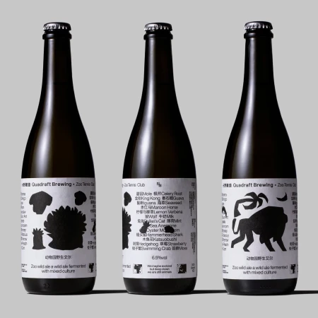 Three bottles of Quidraft Brewing Zoo Tennis Club ale with animal-themed labels stand against a grey background. 