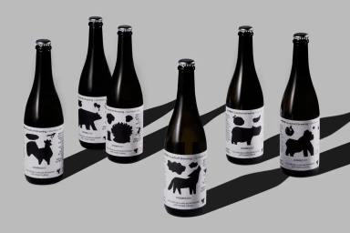 Six dark glass beer bottles with white labels featuring black animal silhouettes arranged on a grey surface.