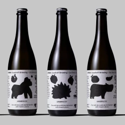 Three dark glass beer bottles with white labels featuring black animal silhouette graphics against a grey background.