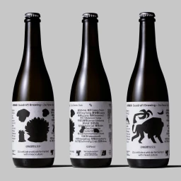 Three dark glass beer bottles with white illustrated labels standing against a neutral grey studio backdrop.