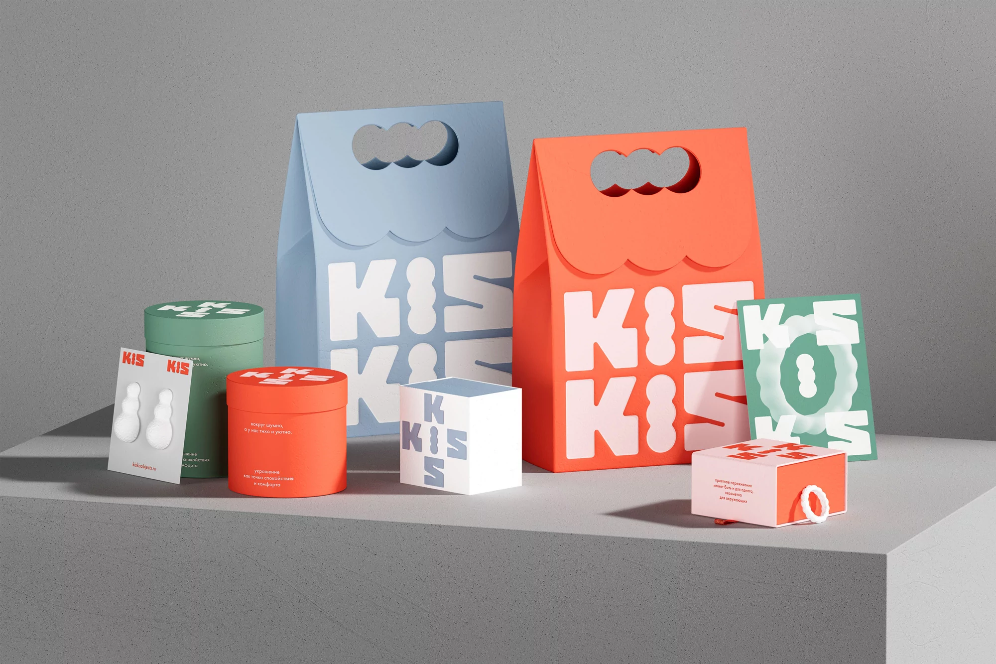 Product packaging featuring KIS branding in shades of orange, blue, green, and white, arranged on a gray surface in a studio setting.