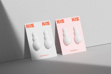 Two product packaging cards with white sculptural objects on gray surface in soft natural light.