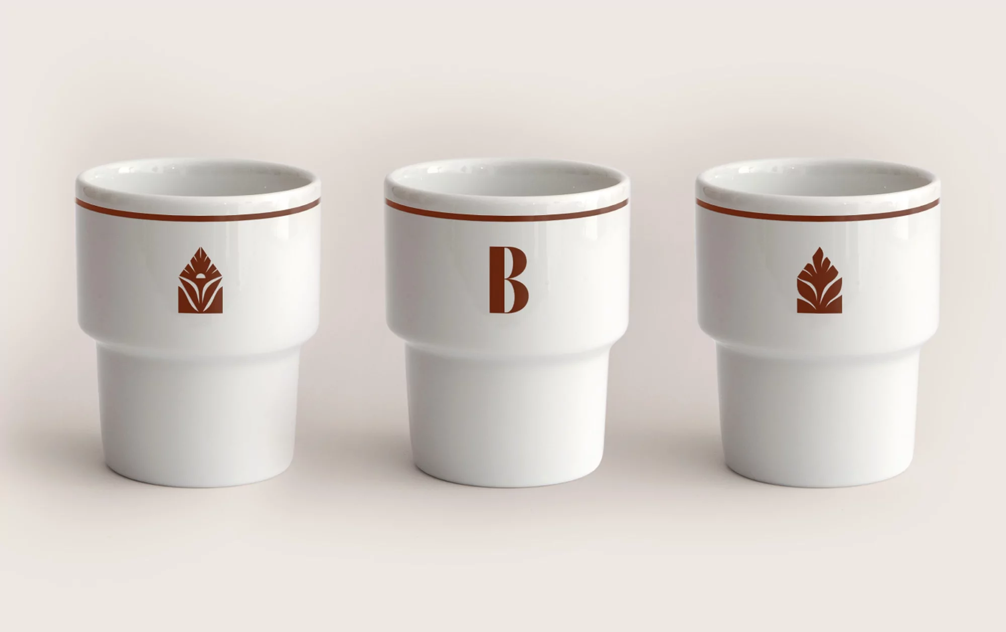 Three white ceramic cups with brown accents and minimalist designs, arranged on a neutral surface in a simple, elegant composition.