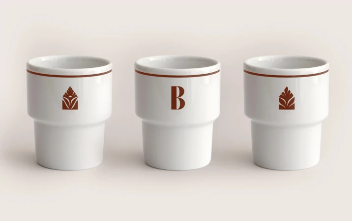 Three white ceramic cups with brown accents and minimalist designs, arranged on a neutral surface in a simple, elegant composition.