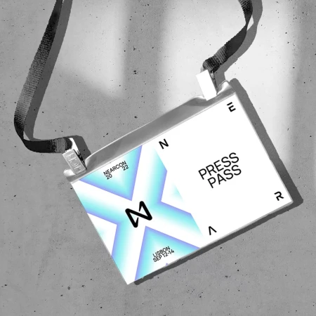 Press pass for Nearcon 2022 in Lisbon on a lanyard against a gray concrete background featuring the event logo and dates.