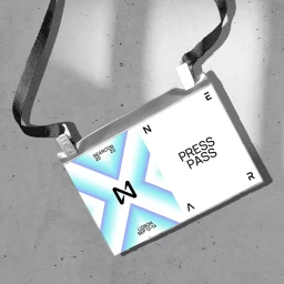 NEARCON press pass hanging on a textured grey concrete wall under harsh natural lighting