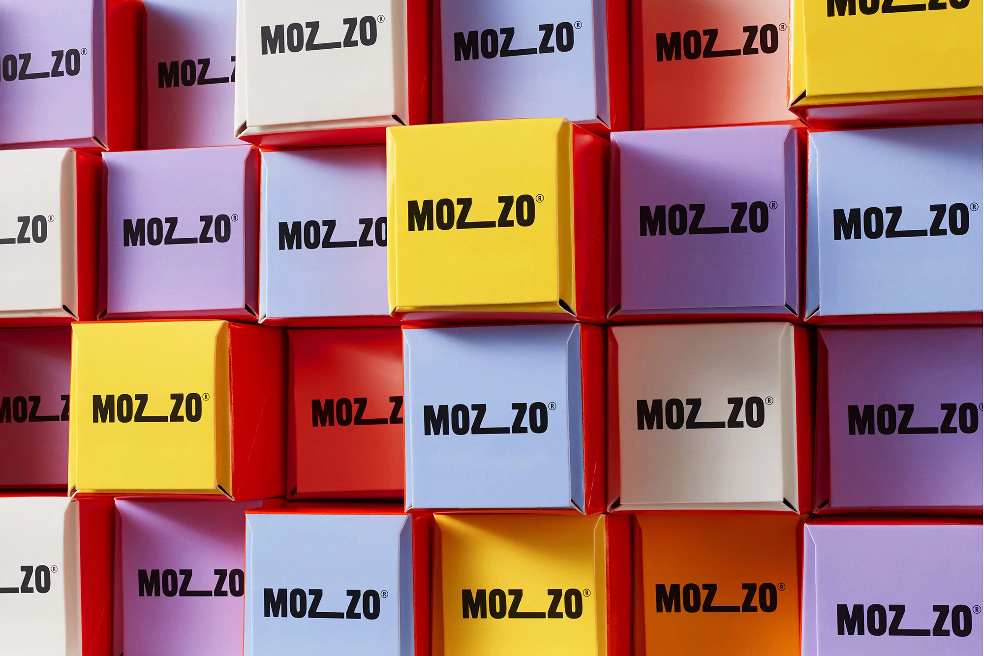 Close-up of multicolored square boxes stacked tightly, each featuring the brand name 'MOZ_ZO' in bold black letters on the front face.