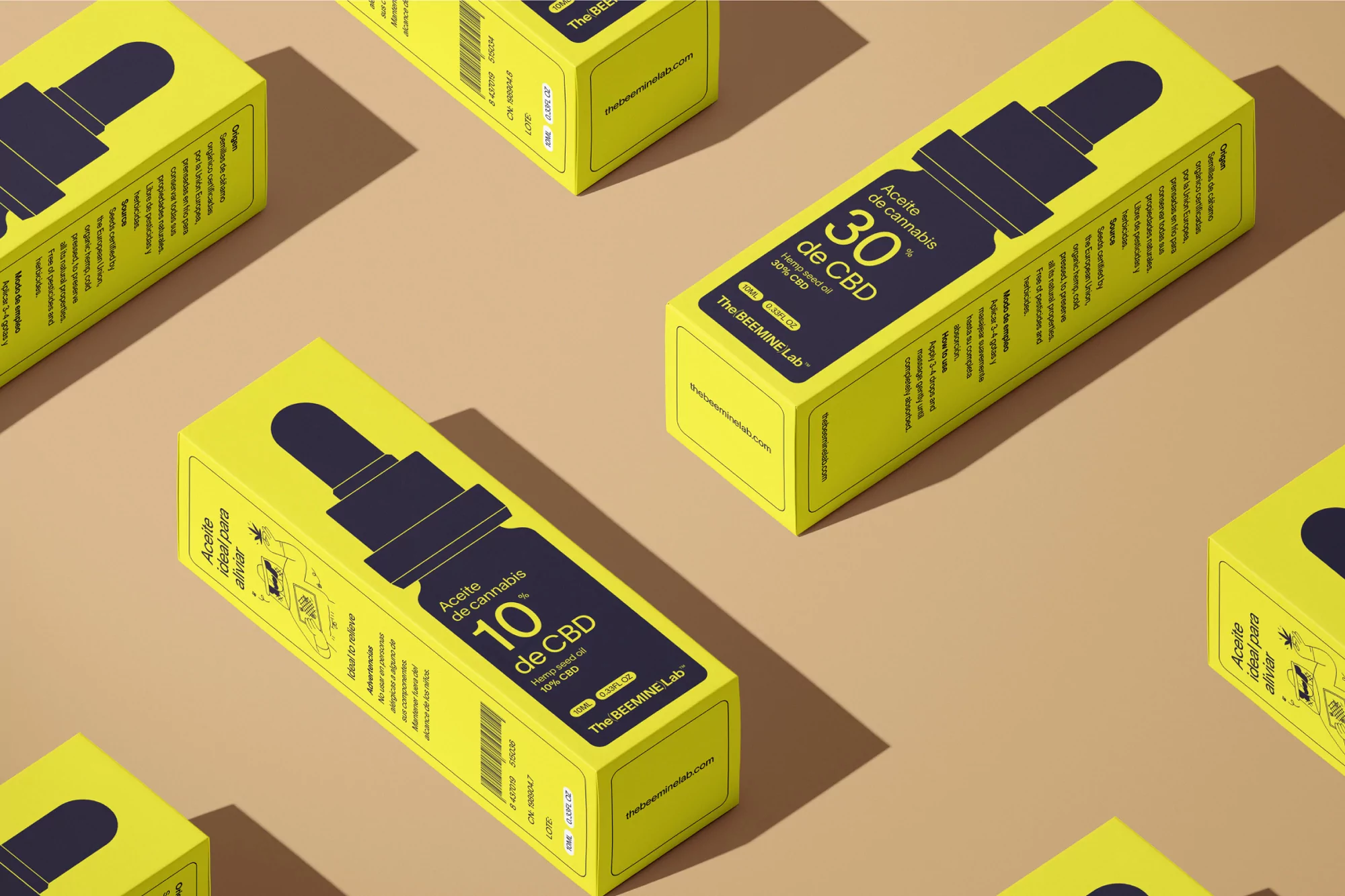 Several yellow boxes of cannabis oil with a dark purple label against a tan background in a studio product shot.