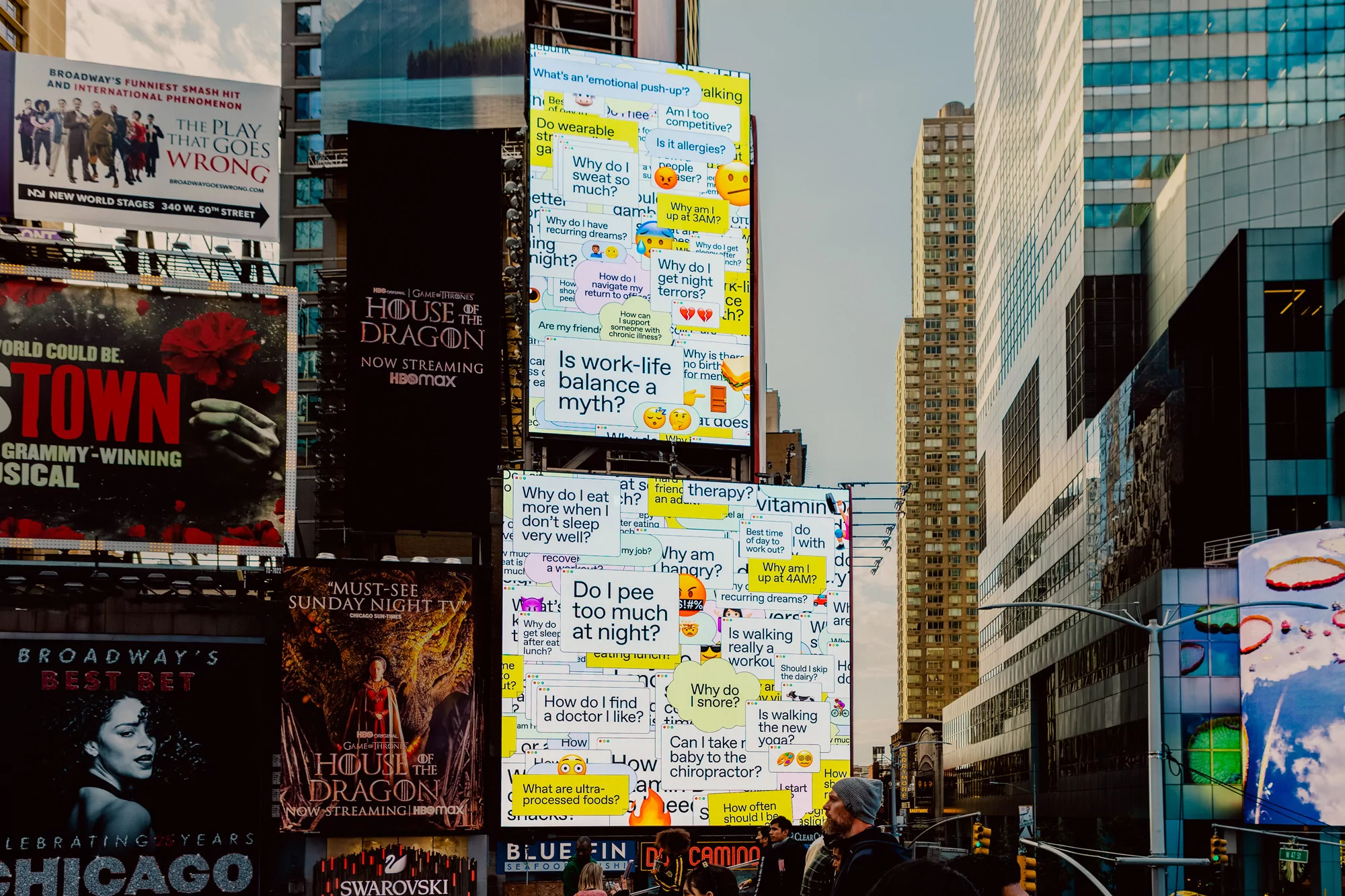 Times Square displays digital billboards with bright text and advertisements alongside modern high-rise buildings and pedestrians below.