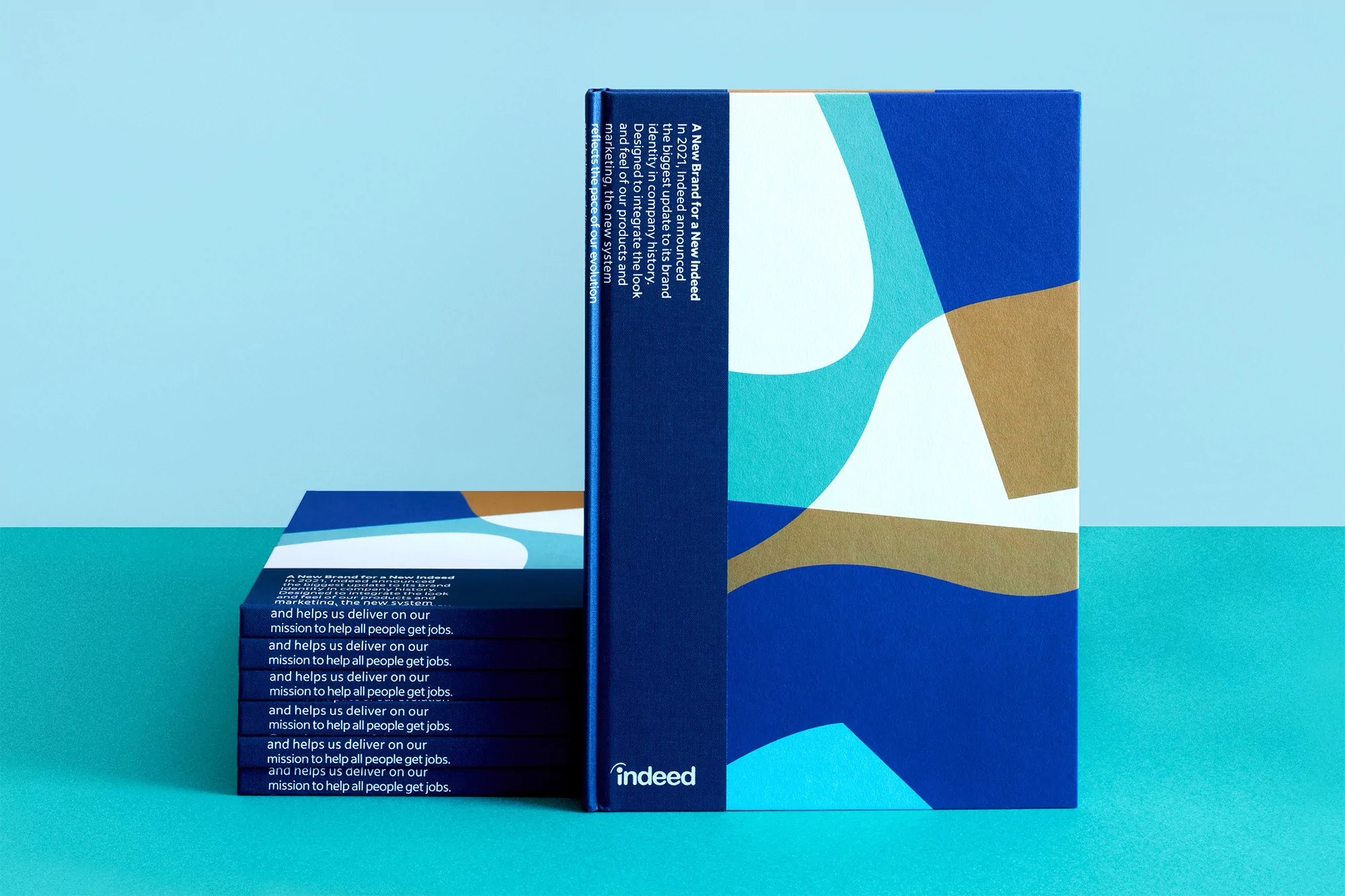 Stack of new branding books for Indeed featuring modern abstract designs and the company logo. Design supports the job search mission.