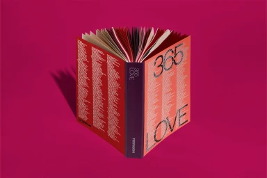 An open book titled 365 Love by Fedrigoni standing vertically against a solid pink background casting a sharp shadow.