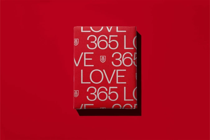Red paper box with printed white 365 and LOVE typography set against a matching red background casting a soft shadow.
