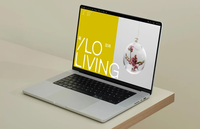 Silver laptop displaying an ILO Living brand identity website on a minimalist beige desk.