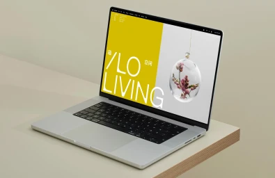 Silver laptop displaying an ILO Living brand identity website on a minimalist beige desk.