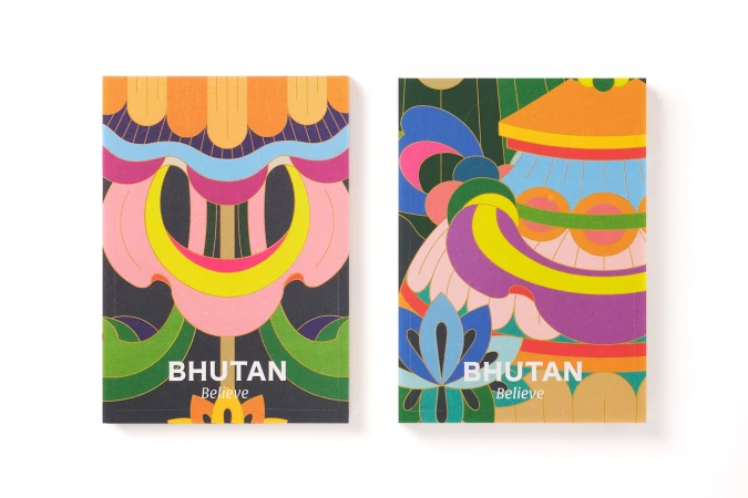Two colorful artistic greeting cards with geometric designs and text 'Bhutan Believe', set on a clean white surface, offering a vibrant, cheerful aesthetic.