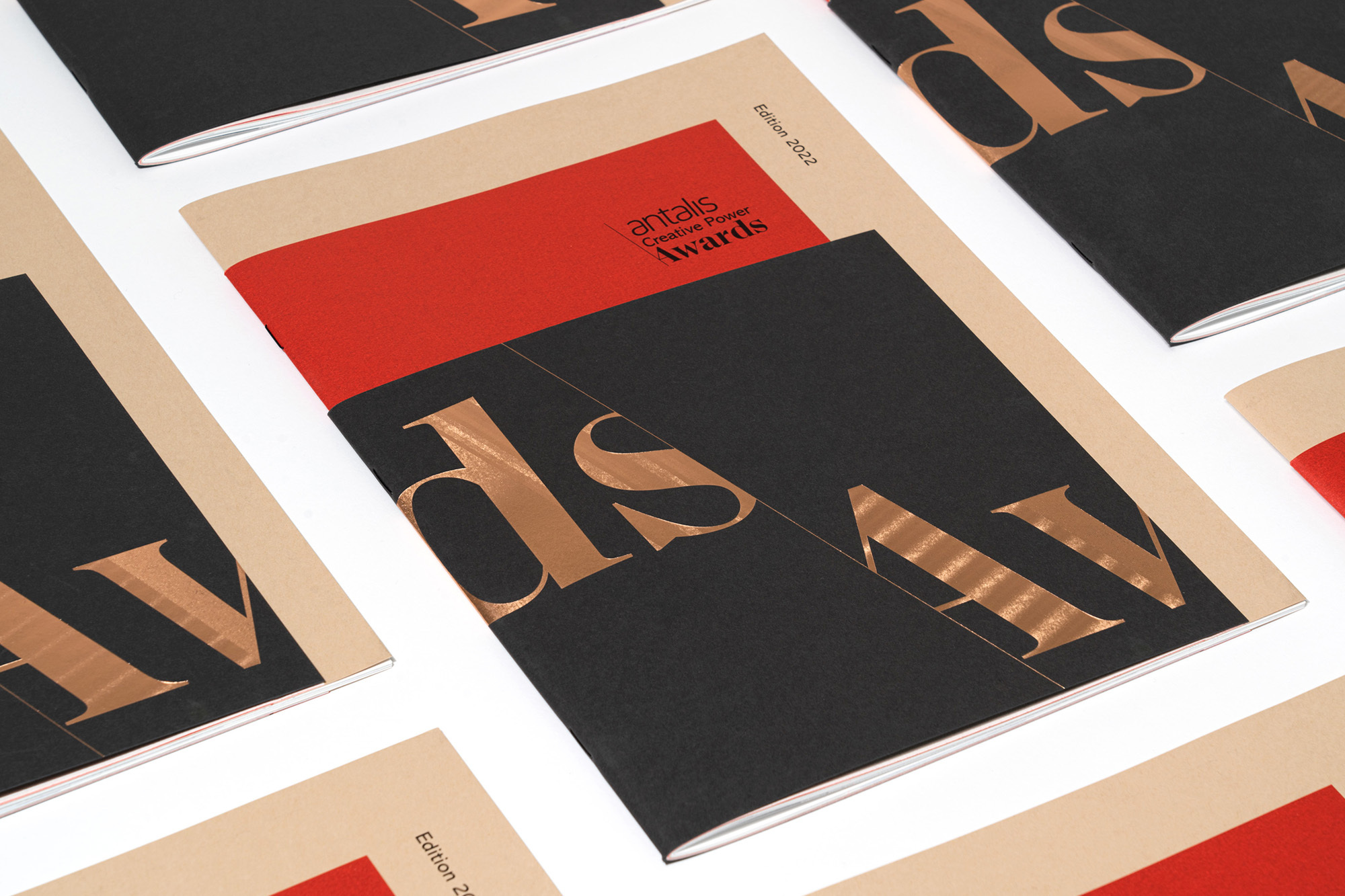 Stack of Antalis Creative Power Awards edition 2022 magazines with black, red, and beige covers, arranged on a white surface.