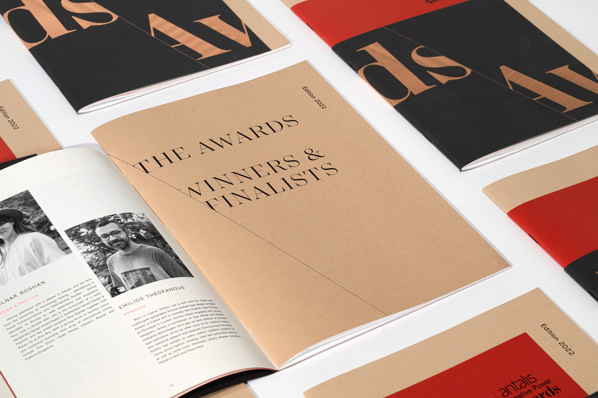 Stack of tan and red awards magazines titled 'The Awards Winners & Finalists Edition 2022' on a white surface, displayed indoors.