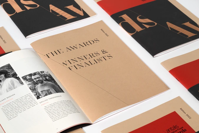Stack of tan and red awards magazines titled 'The Awards Winners & Finalists Edition 2022' on a white surface, displayed indoors.