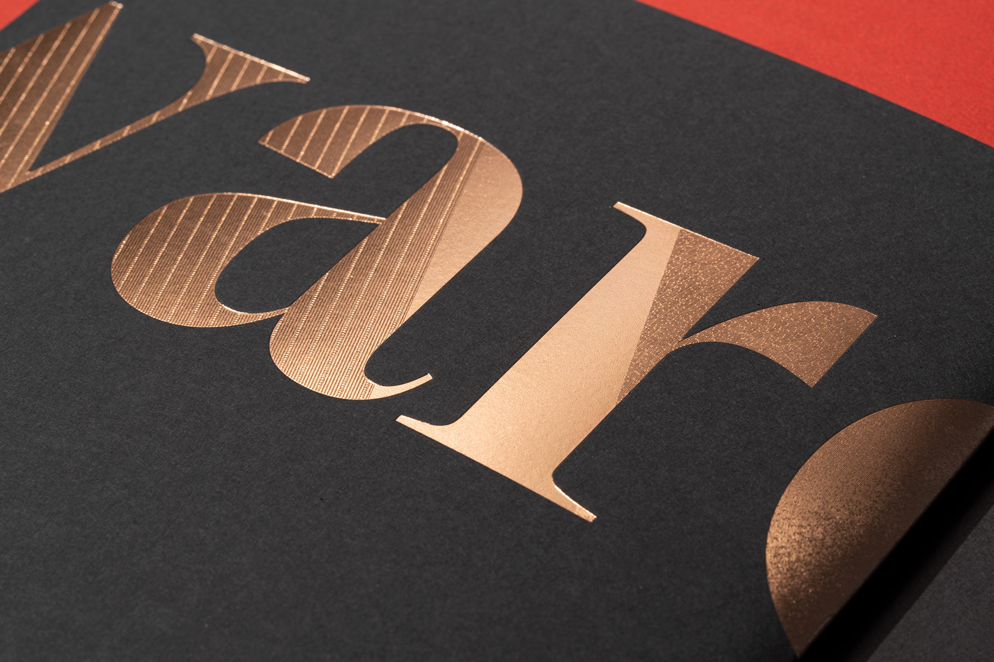 Close-up of elegant black paper with copper foil stamped lettering creating a sophisticated tactile design for invitations or branding.