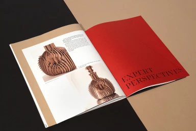 An open magazine spread featuring structured paper art objects on the left and a vibrant red cover page with bold black typography.