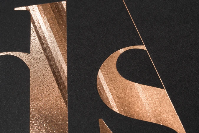 Close-up of copper foil typography printed on dark textured paper stock for Antalis brand identity design