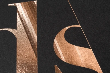 Close-up of copper foil typography printed on dark textured paper stock for Antalis brand identity design