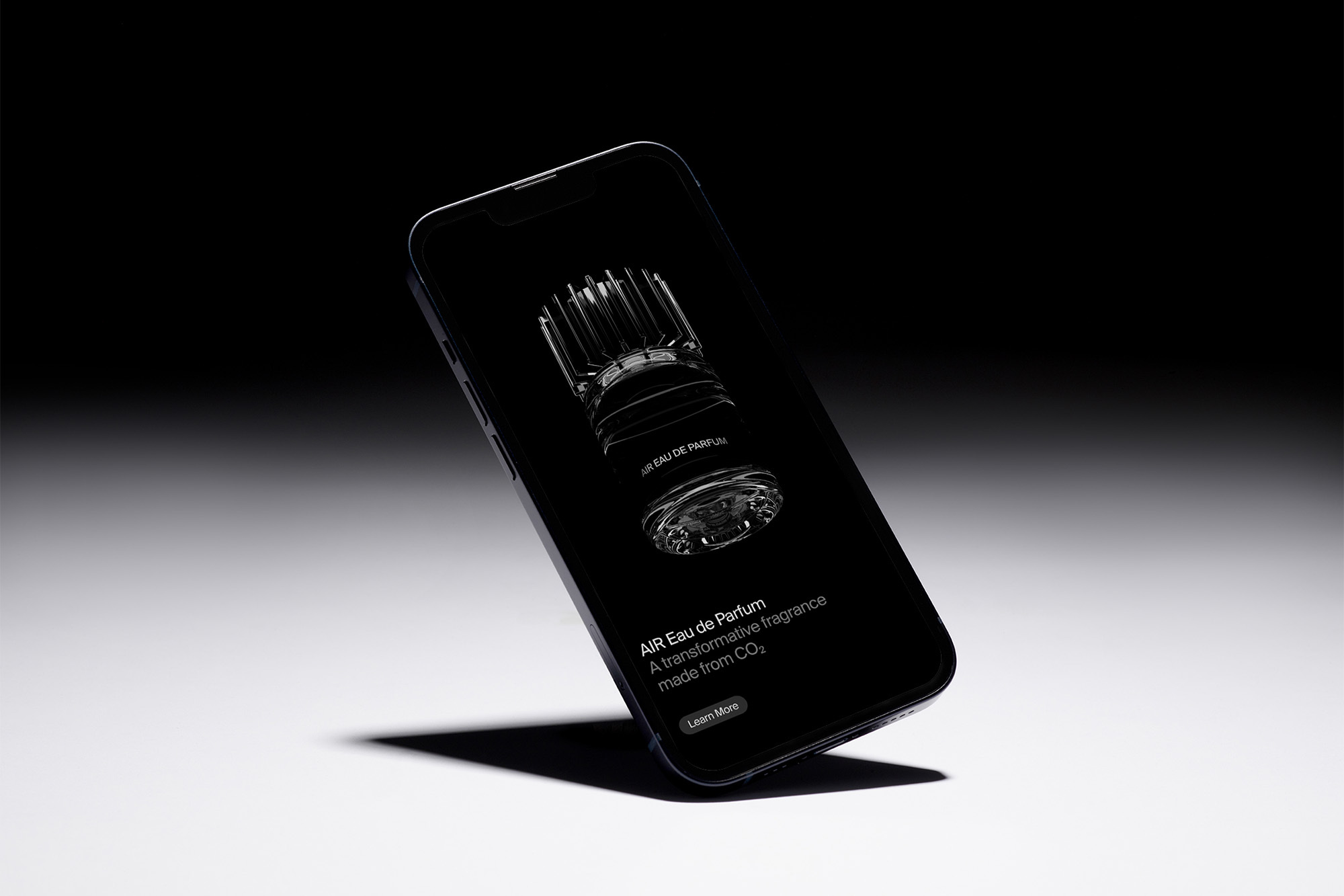 Elevated view of an iPhone displaying a 3D rendering of a perfume bottle, set against a gradient background, creating a stylish product shot.