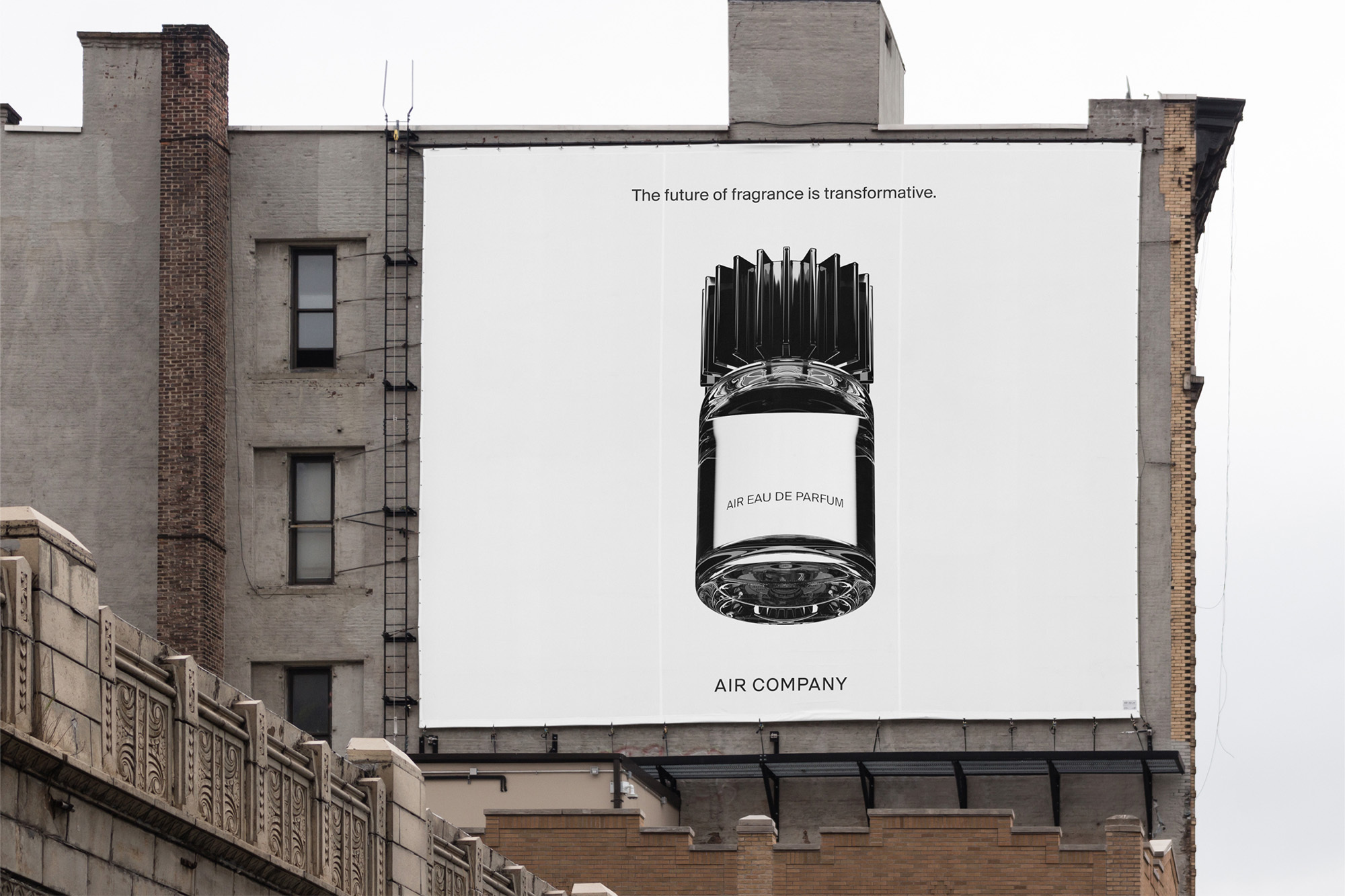 Outdoor advertisement on a building features an oversized fragrance bottle against a bright white backdrop with visible brand and product names.