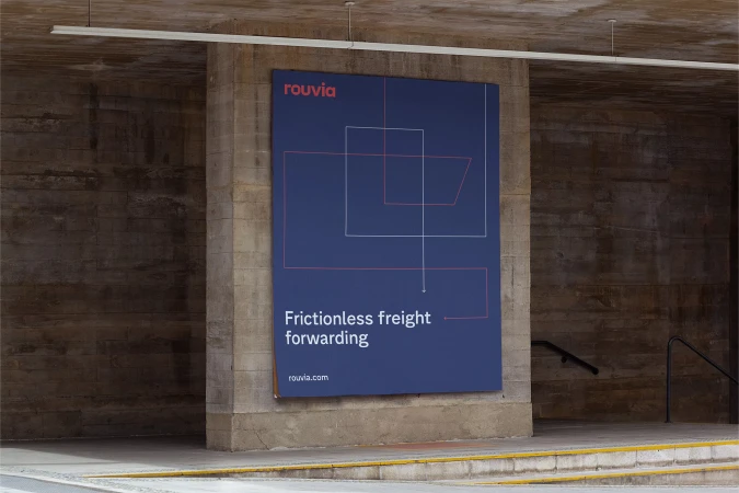 Outdoor advertisement on concrete wall features 'Rouvia' logo, geometric lines, and text promoting frictionless freight forwarding services.