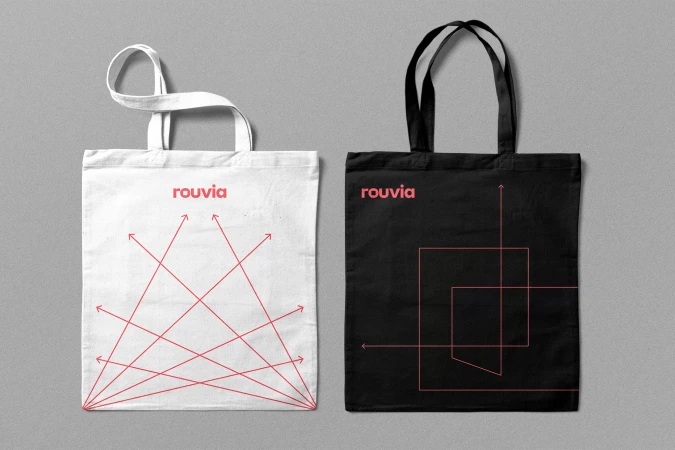 Two cotton canvas tote bags, one white with red graphic lines and one black with pink linear graphics, displayed against grey