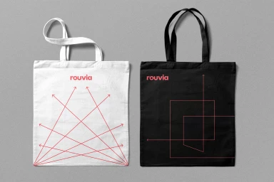 Two cotton canvas tote bags, one white with red graphic lines and one black with pink linear graphics, displayed against grey