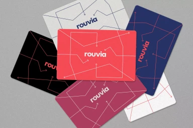 Top-down view of six colorful branded cards featuring linear directional graphics and the Rouvia logo on textured grey background.