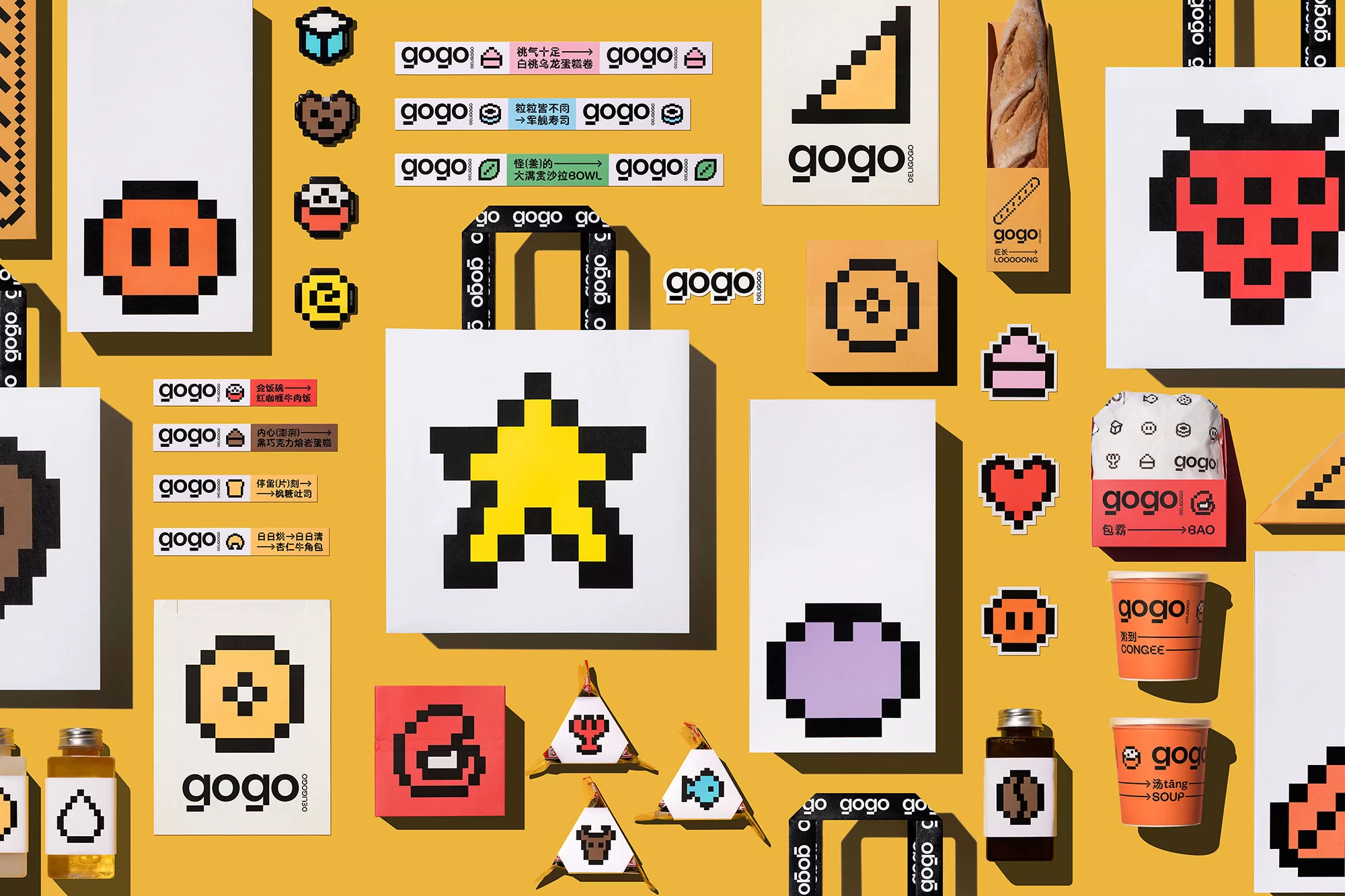 Flat lay of pixel art-style food illustrations, gogo brand logos, food containers, and product packaging against a yellow backdrop.