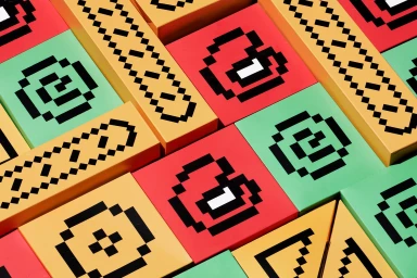 Colorful geometric packaging blocks featuring pixelated black graphic patterns on red yellow and green surfaces.