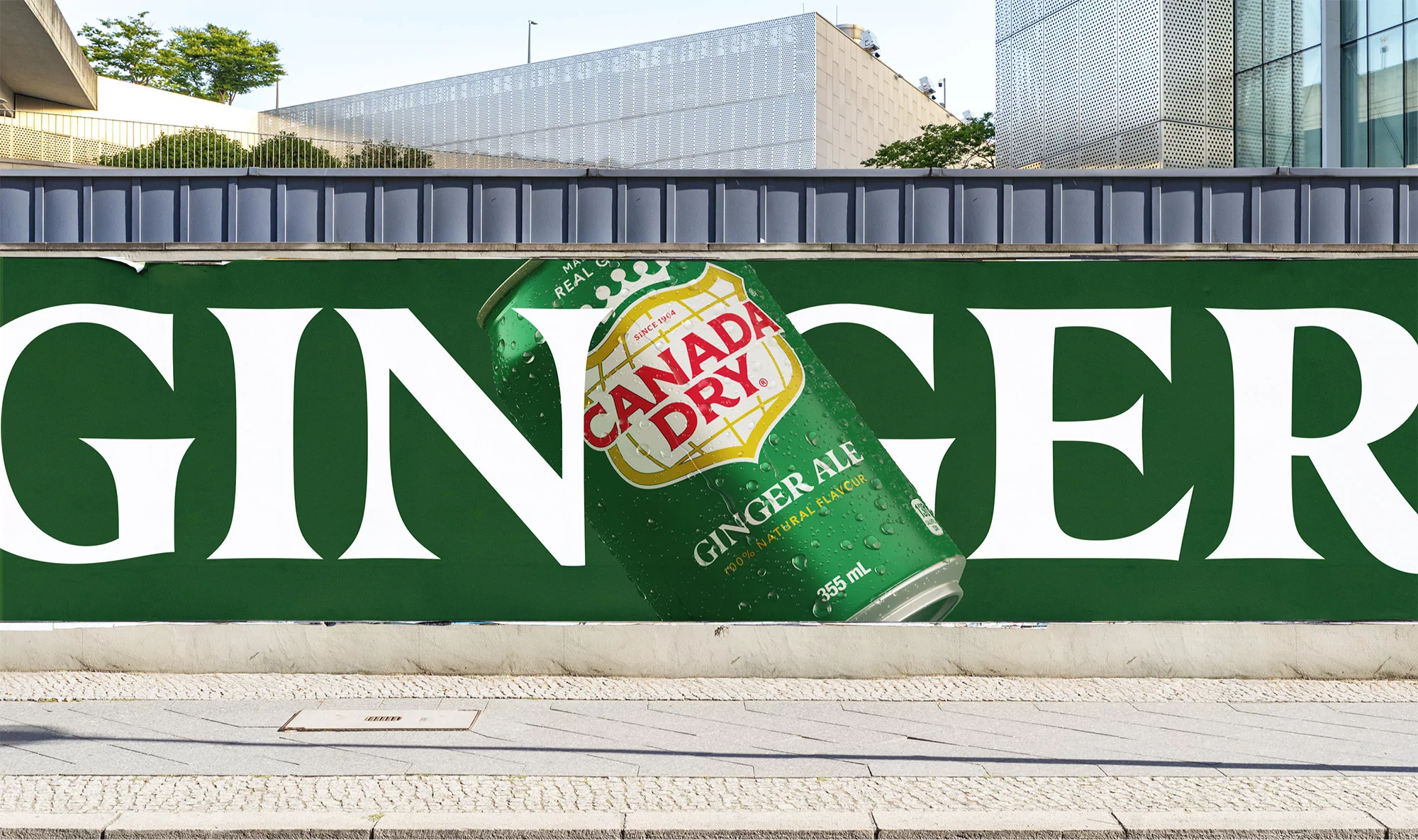 Canada Dry Ginger Ale can displayed as large promotional ad on a city street with building in the background, bright daytime lighting.
