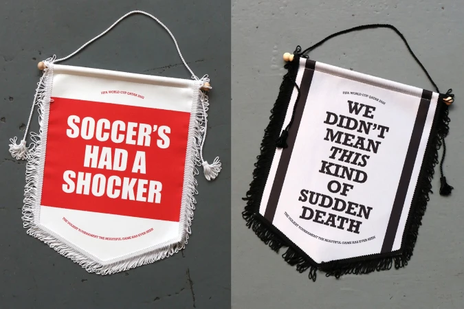 Two decorative sports banners with fringe, featuring text about soccer, one red and white, the other black and white, on gray.